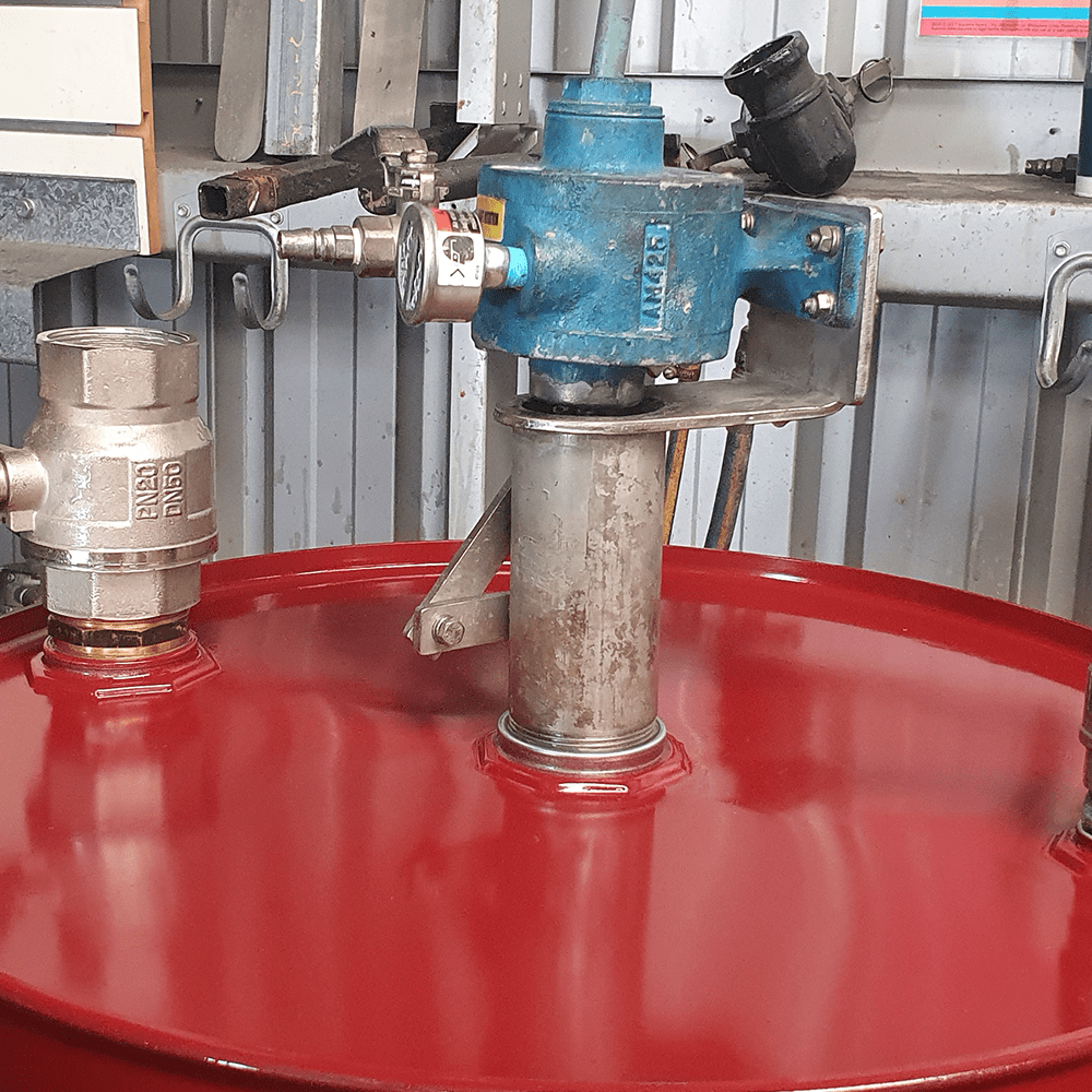A pneumatic drum mixer mounted through the bung opening of a red 200L fluid drum. 