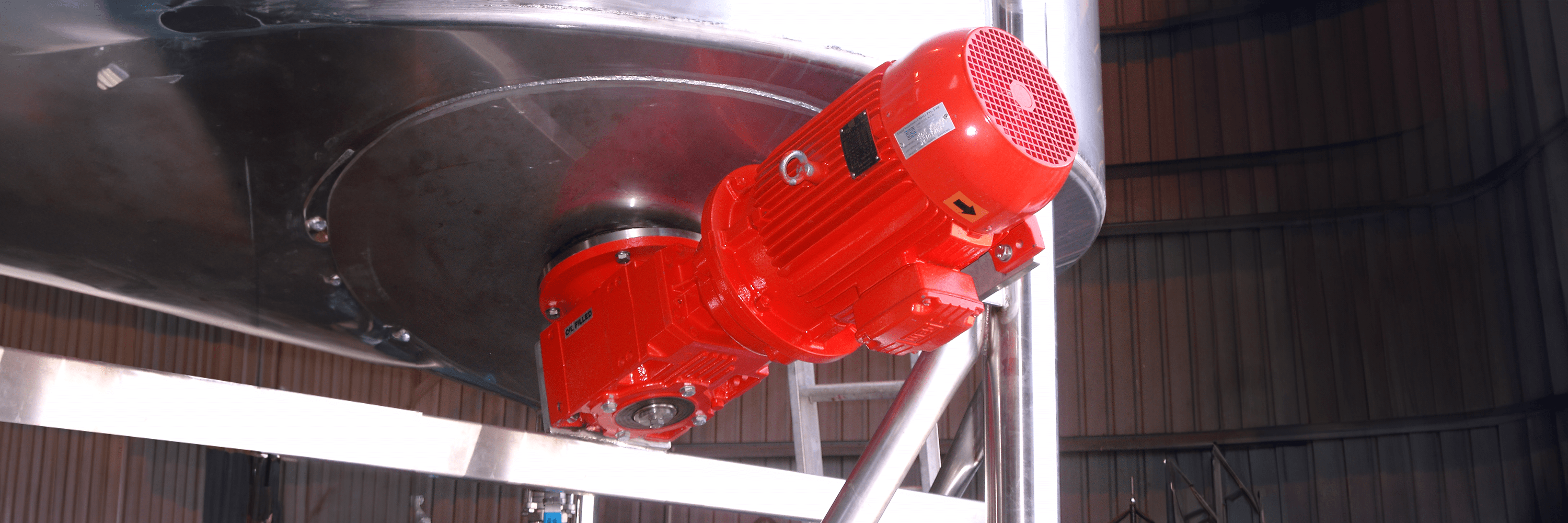 A base entry mixer with a red flameproof or explosion proof motor, mounted to a cone bottom stainless steel tank.
