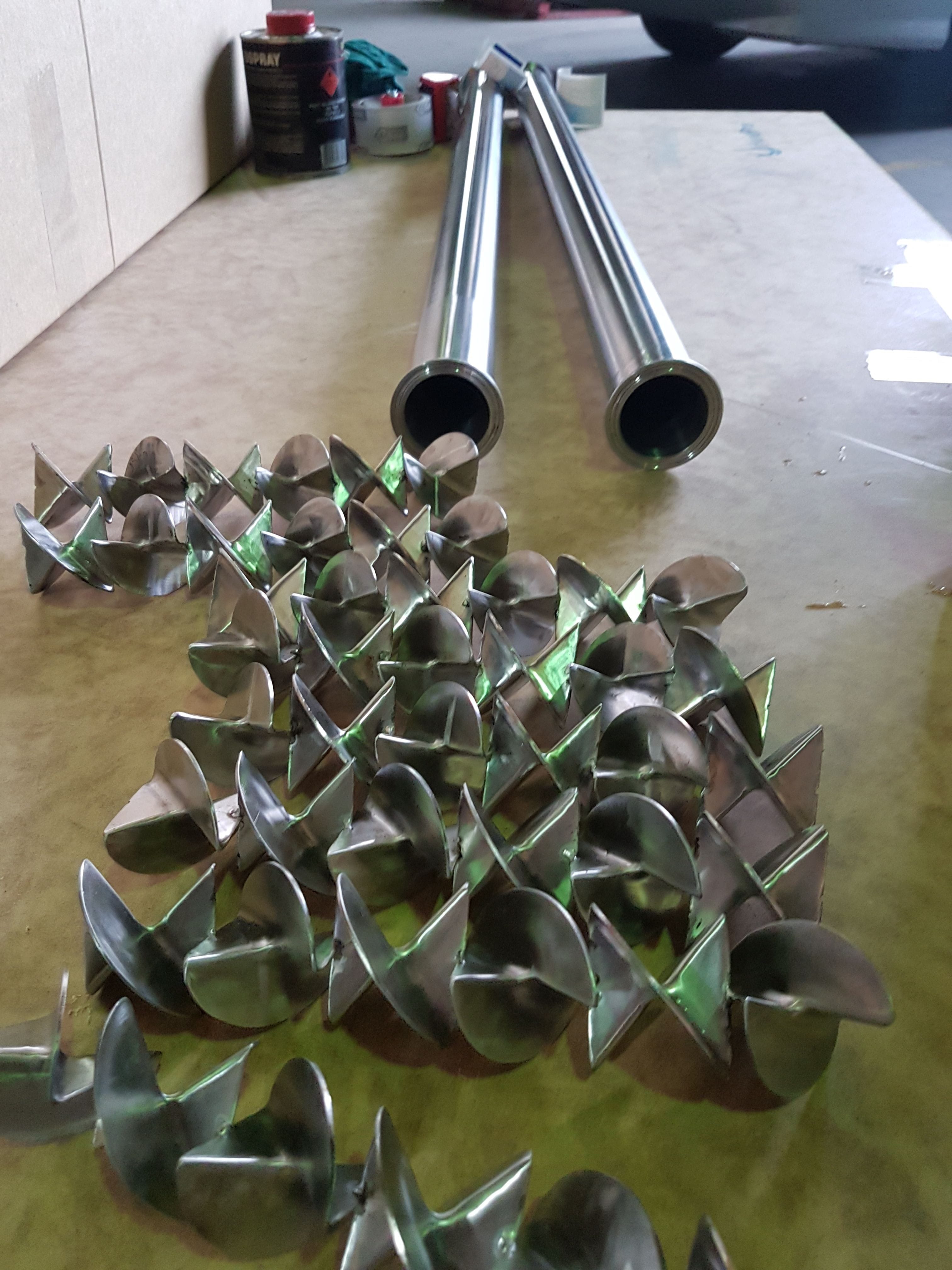 Two stainless steel static mixers beside their mixer elements. The stainless steel  baffles are designed to fit the mixers.