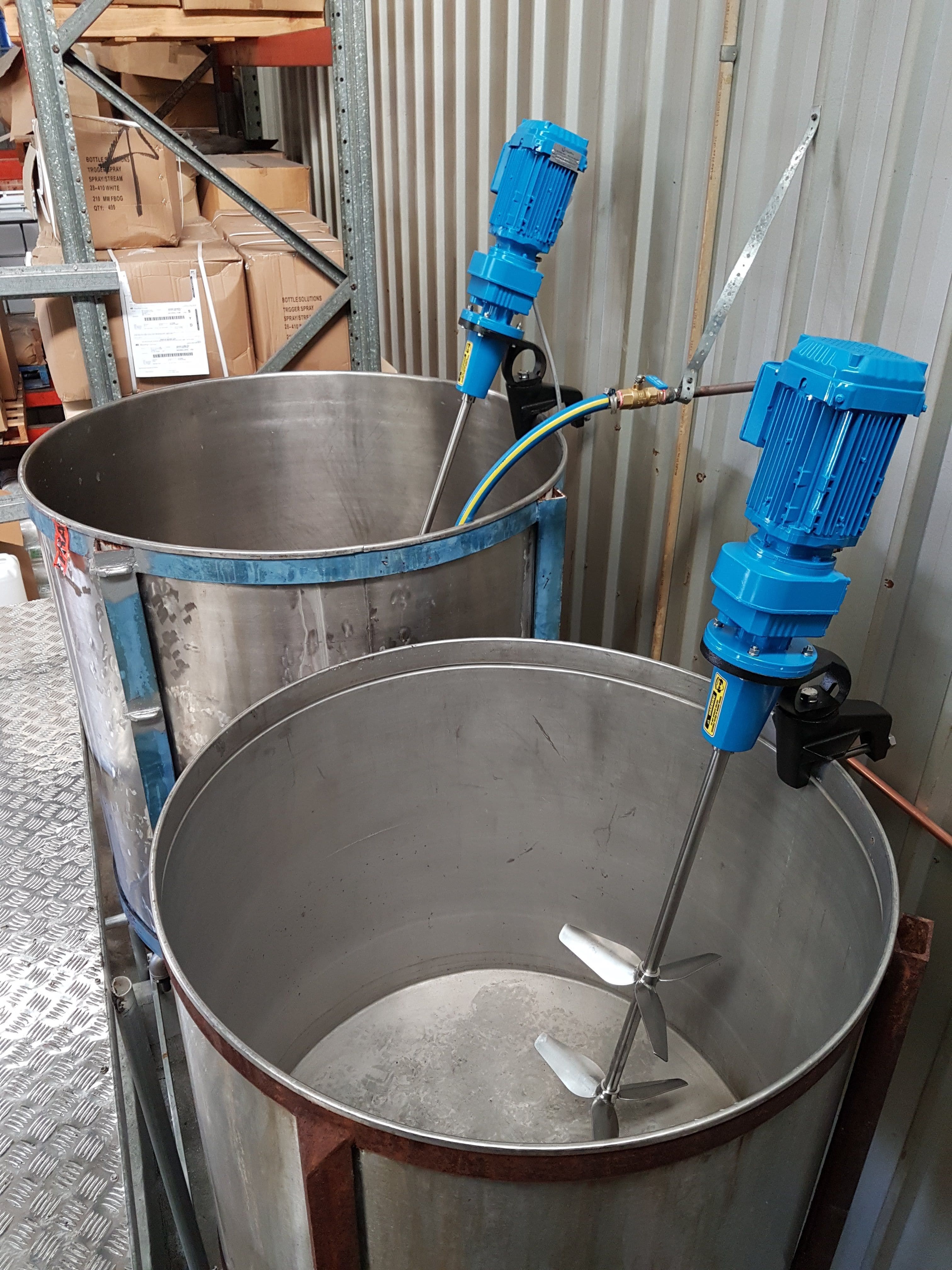 Two FluidPro PS-10 Clamp Mount Mixers attached to open stainless steel tanks which are empty to show the impellers and shaft.